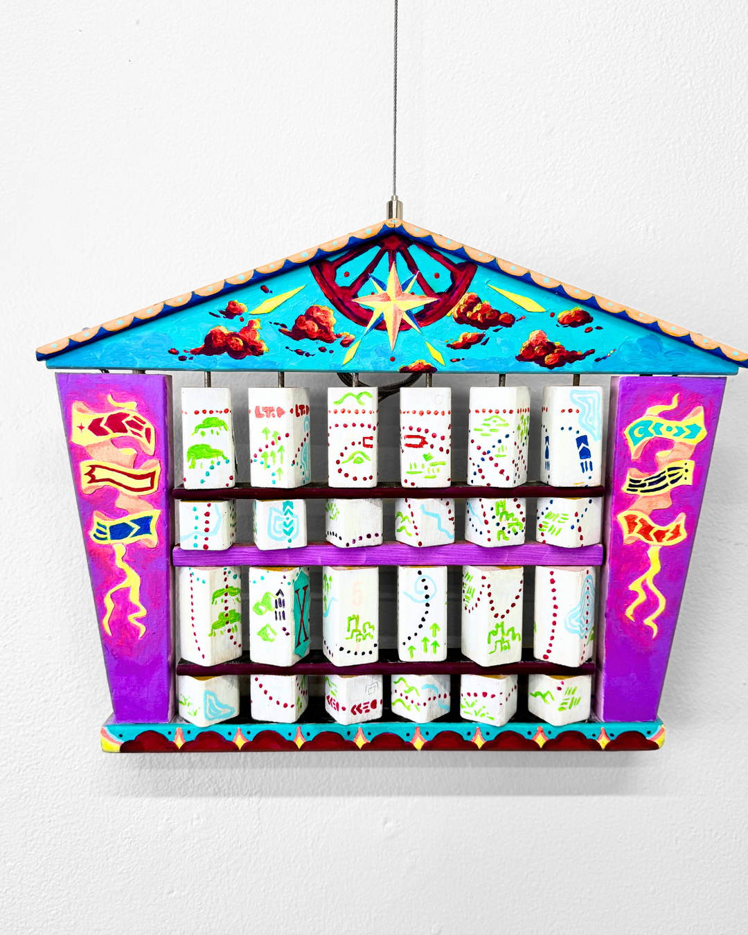 Decorative hanging organizer with colorful design on a white background. The pieces are designed to turn, creating a different image with each spin.