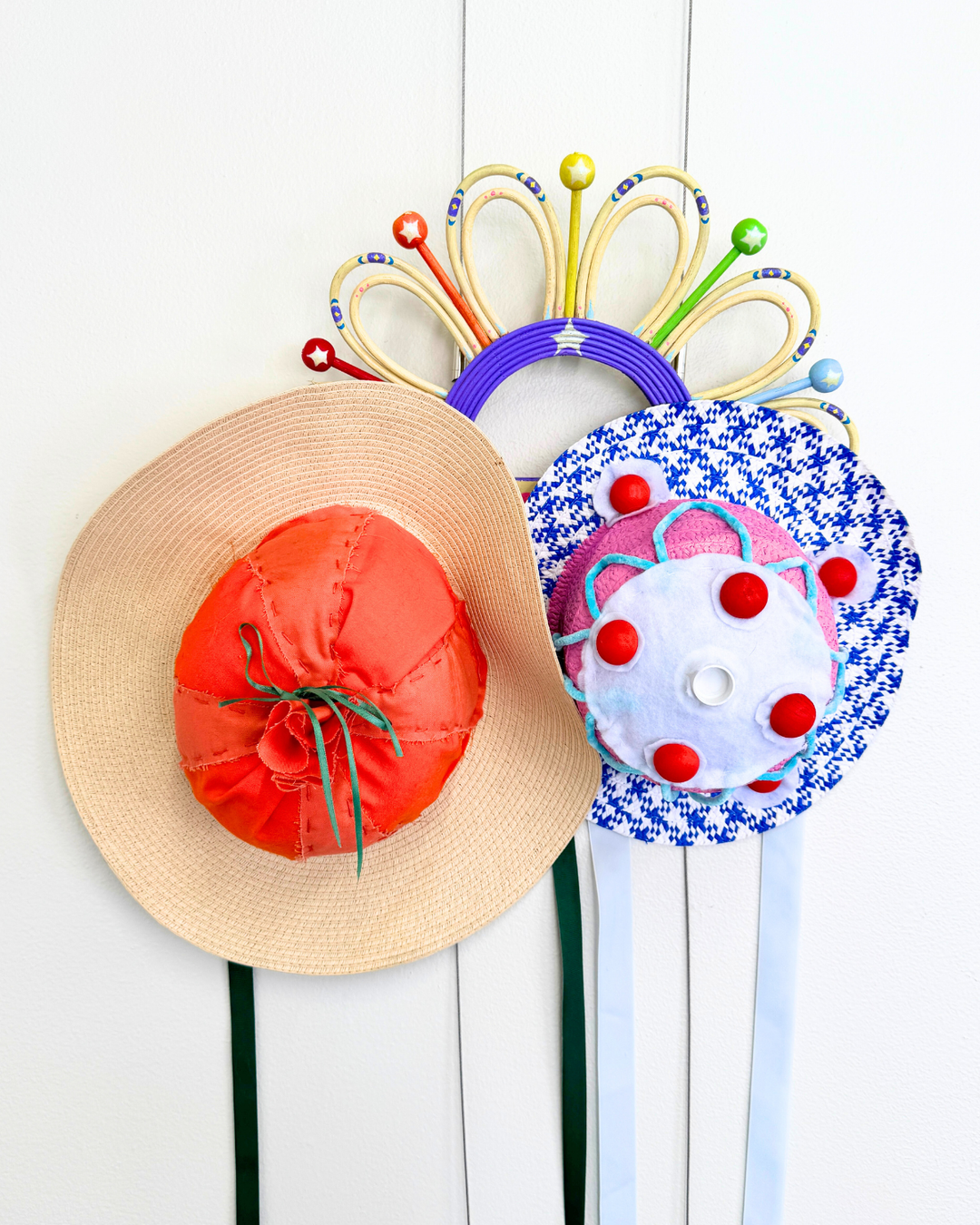 Decorative garden hats with colorful ribbons on a white background. Hats are pinned to cable ties but meant to be taken down and worn for photo opportunities in this gallery display.