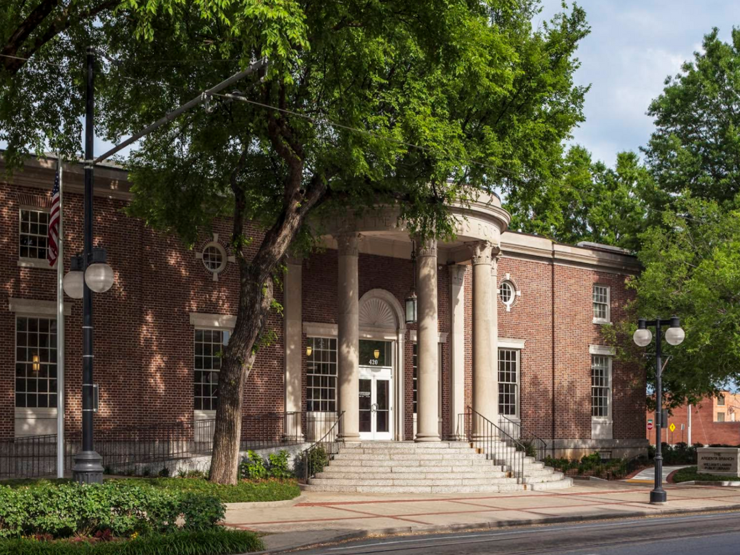 Image featuring Argenta Library's brick building with columns and trees in front on a clear day, located at 420 Main St., NLR AR