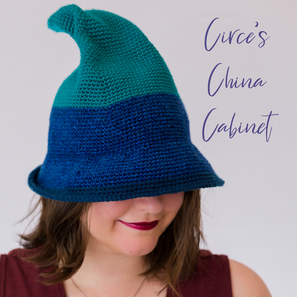 Person wearing a teal and blue crocheted hat with 'Circe's China Cabinet' text on a light gray background