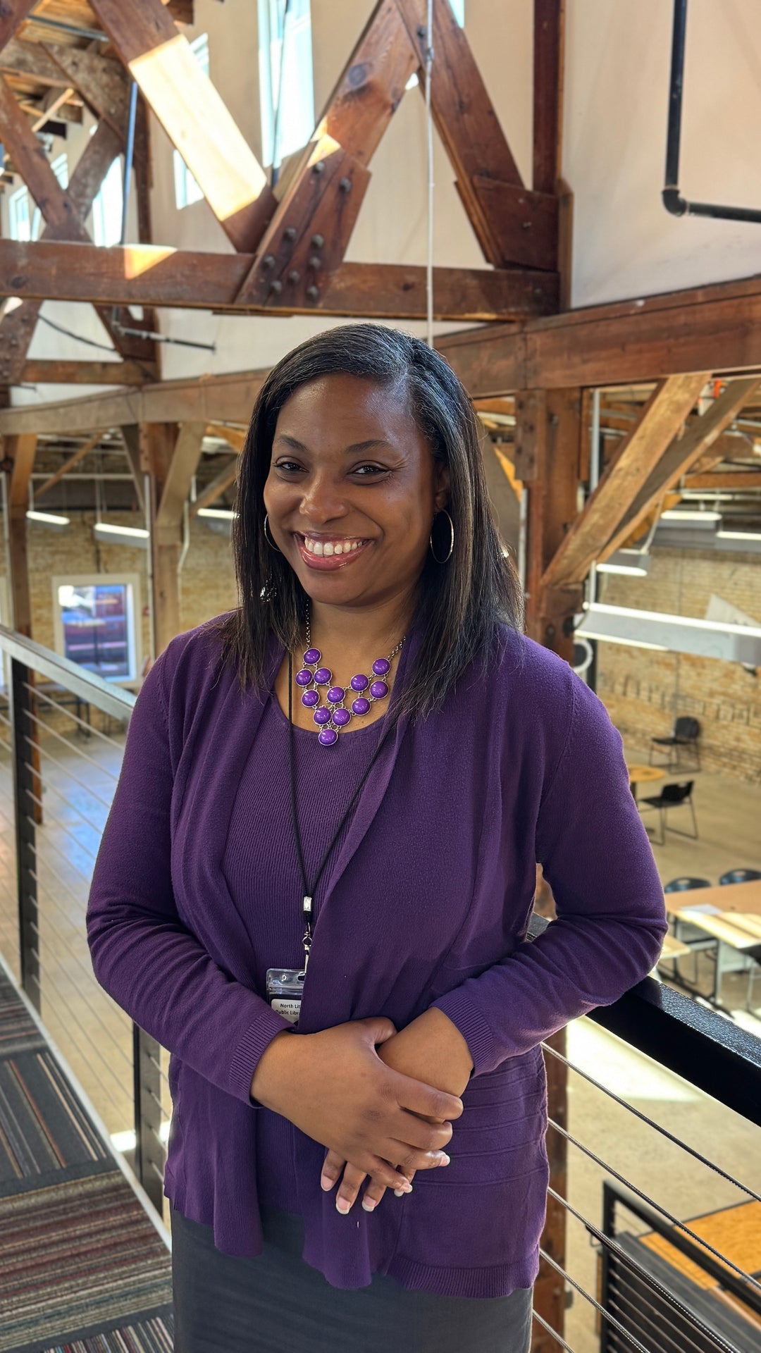 DeLisa, workforce development manager, Woman in a purple cardigan standing in the Hub building with wooden beams in background