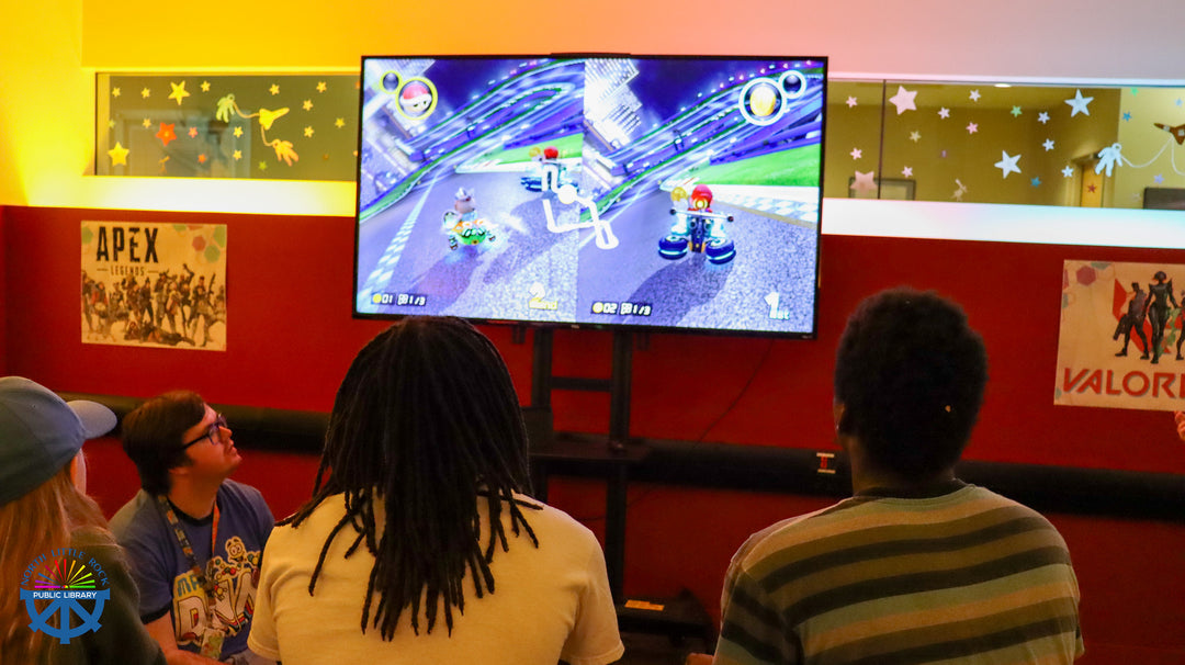 People playing a video game on a screen with colorful walls and posters in the background.